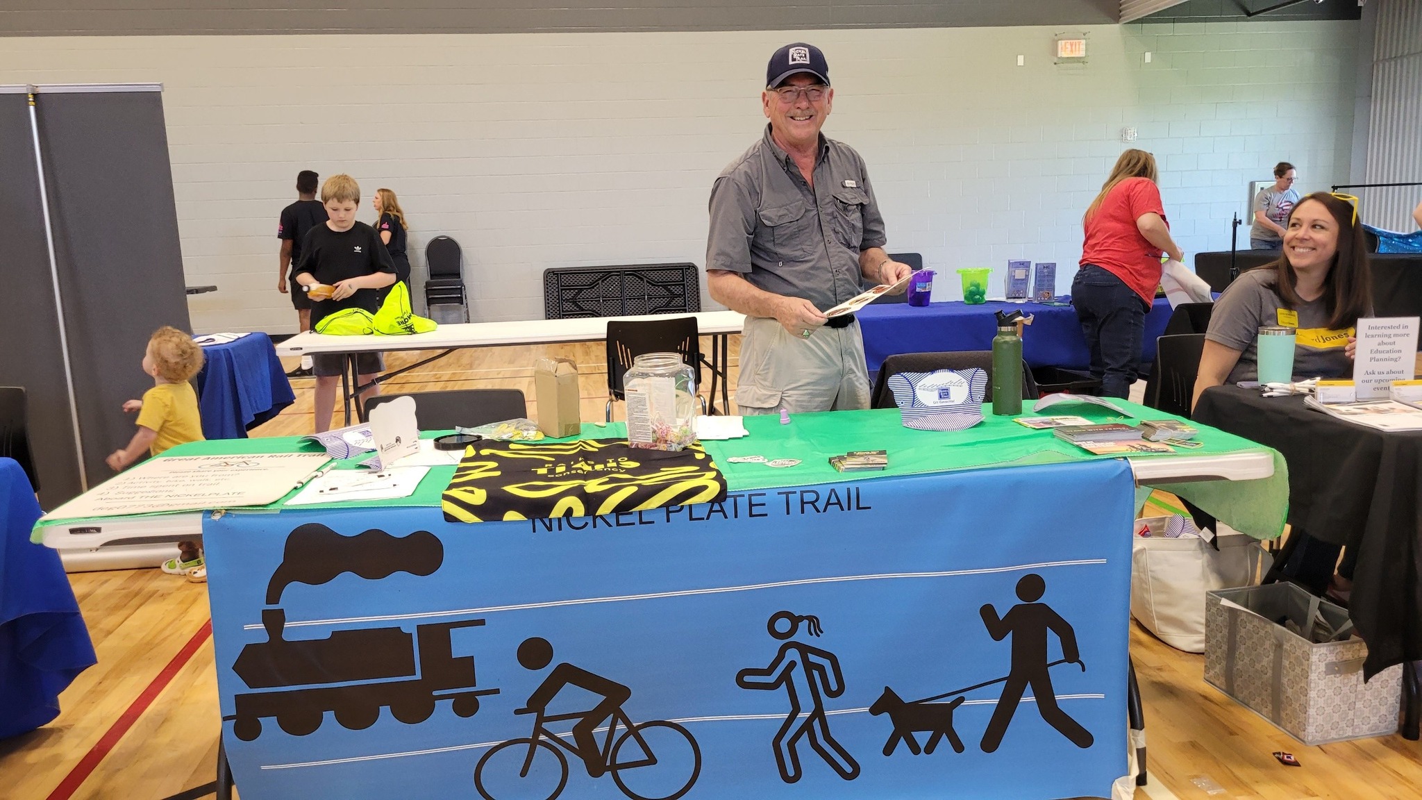 NPT volunteer at the Nickel Plate Trail display table with banner showing trail activities
